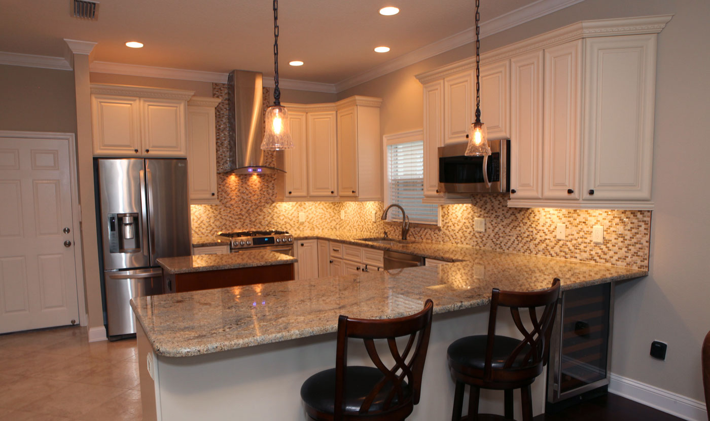 A kitchen with white cabinets and granite counter tops.