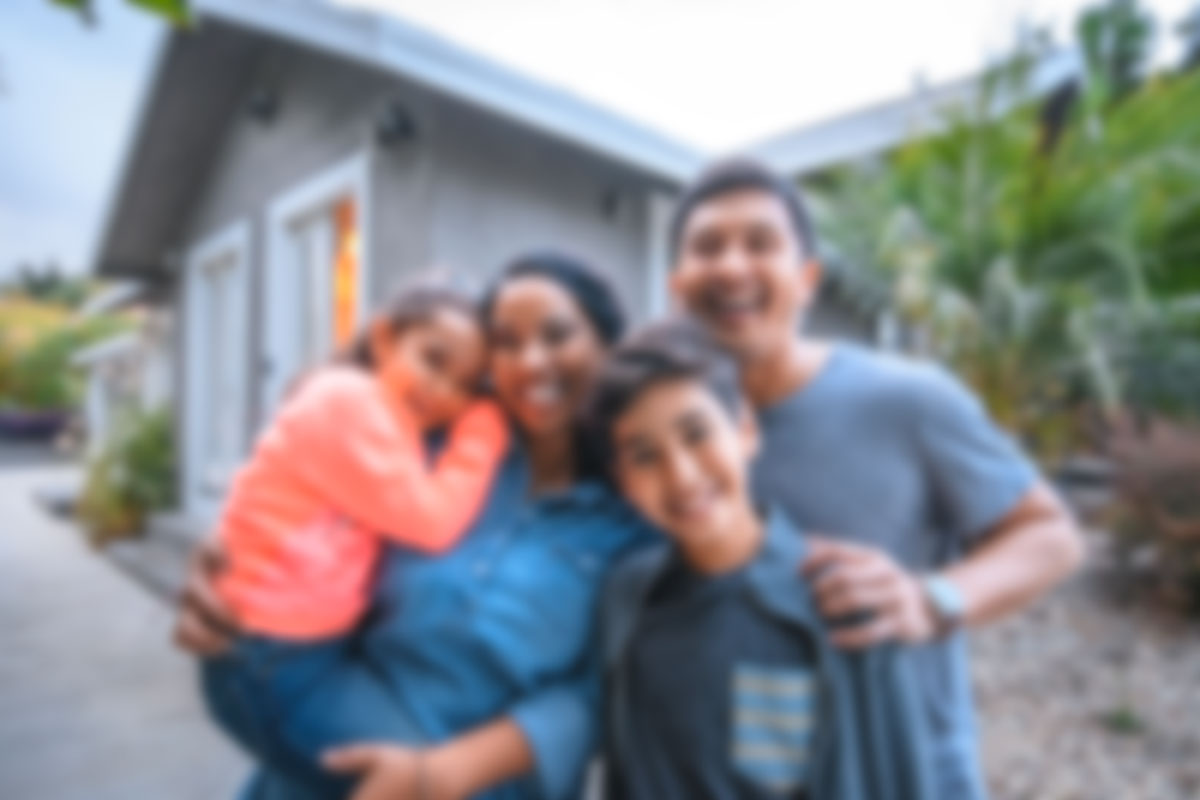 A family posing for the camera outside of their home.