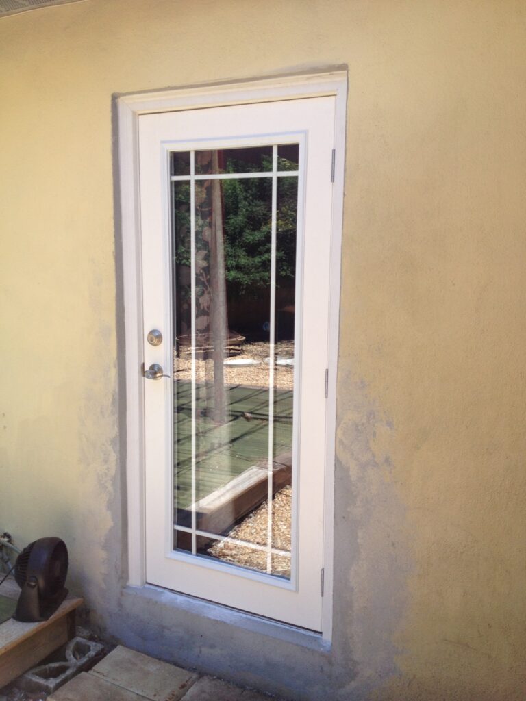 Exterior door with window panes and weather stripping on a stucco home